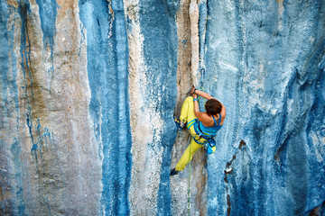Fototapeta premium Rock climber climbing up a cliff