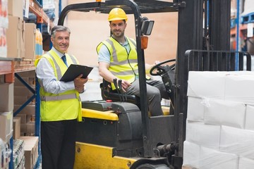 Driver operating forklift machine next to his manager