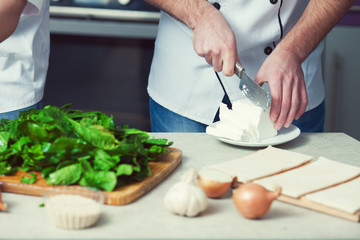 Vegetarian bakery concept. Chef's hands cutting feta cheese