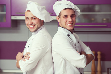 Portrait of two funny working men in cook uniform posing