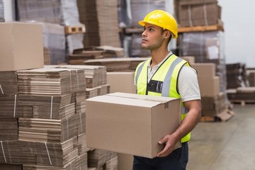 Worker carrying box in warehouse