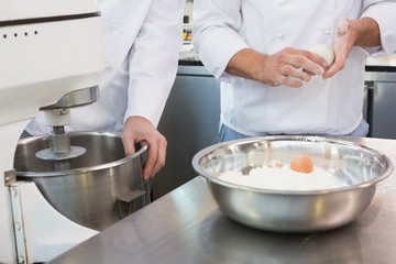 Co-workers making dough with eggs and flour