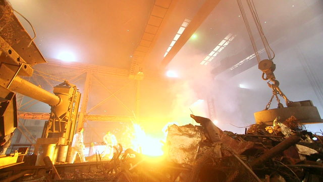 Hard work in the foundry, male worker controlling of Putting and smelting iron in the furnace