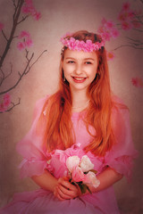 Girl with red hair in a pink dress and with flowers