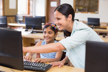 Cute pupil in computer class with teacher