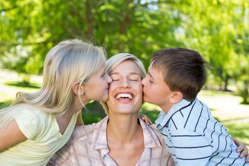 Sister and brother kissing their mother