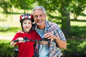 Obraz premium Happy little boy on his bike with his father