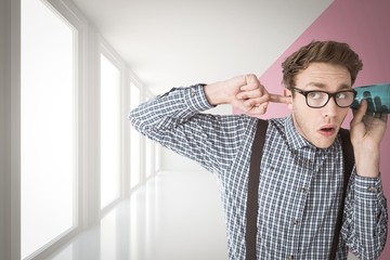 Composite image of geeky businessman eavesdropping with cup