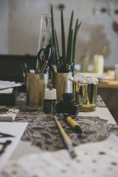 Closeup of artist workstation with pens, markers, scissors, ink