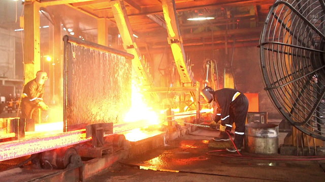 Workers cutting fiery steel blocks