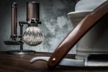 Shaving razors and bowl with foam on wooden background