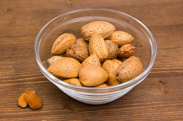 Almonds on glass bowl on wooden table