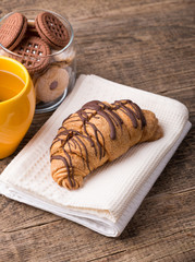 Cappuccino and croissant on wooden table