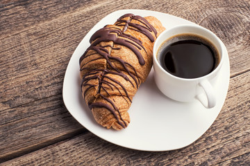 Cappuccino and croissant on wooden table