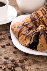 Breakfast with coffee, milk and croissants on wooden table
