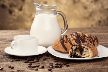 Breakfast with coffee, milk and croissants on wooden table