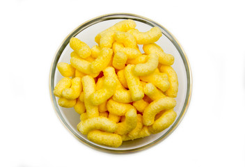 Corn snacks on bowl on white background seen from above