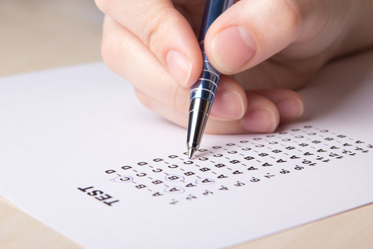female hand filling test score sheet with pen