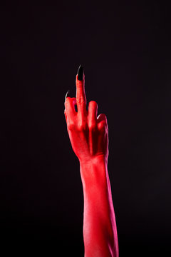 Red devil hand with black nails showing middle finger