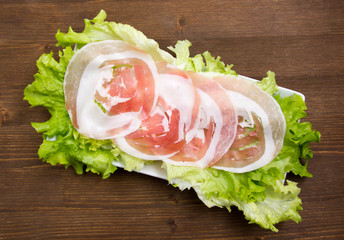 Rolled bacon on salad on wooden table top view