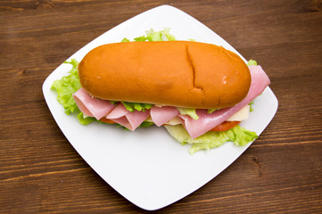 Sandwich with ham and salad on wooden table seen from above
