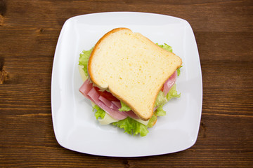 Slices of bread with ham and salad on wood from above