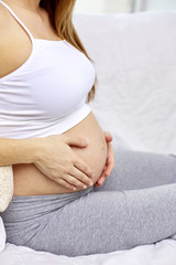 close up of pregnant woman with bare tummy at home