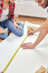 close up of happy couple measuring wallpaper