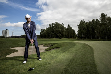 Young handsome business man playing golf outdoors