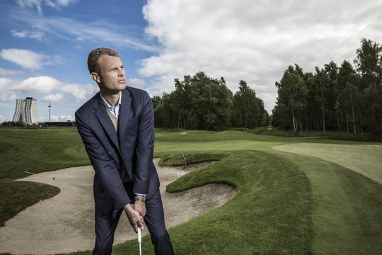Young handsome business man playing golf outdoors