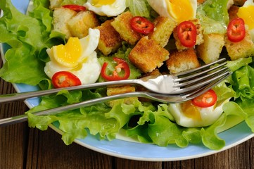 Salad Caesar with eggs, chili pepper and two forks closeup