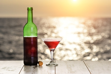 Bottle and glass of red wine sea ocean on sunset