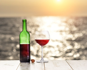 Bottle and glass of red wine sea ocean on sunset