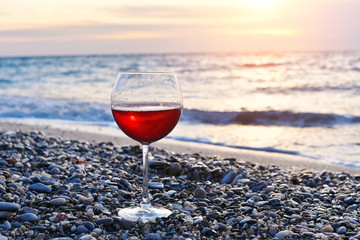 glass of wine on the beach at colorful sunset