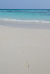 White sand beach and crystal clear water with footprint