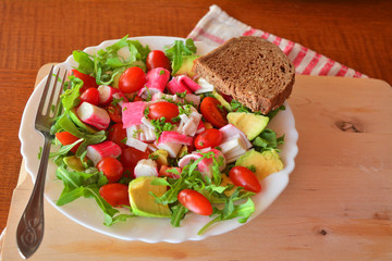 Mixed vegetable salad with crab sticks and avocado
