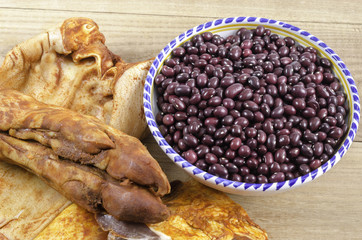 Marinated rack, ear, foot of pig and red edible bean over wood.