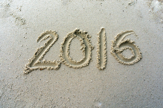 Year 2016 written on the sand at beach