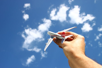 Naklejka premium close up photo of woman's hand holding toy airplane against blue