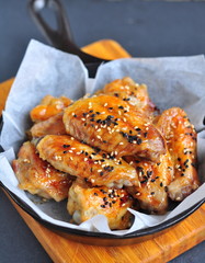 Chicken wings in a sweet and sour sauce with sesame on the pan