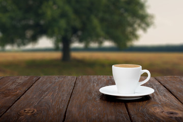 Coffee on wooden table with beautiful field background