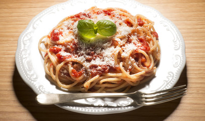 dish with spaghetti and tomato sauce on the wooden table