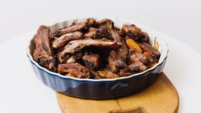 Baked meat ribs with carrots on a large plate on a white