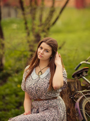 Beautiful young woman in dress sitting on grass near old vintage