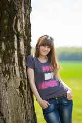 Smiling brunette woman leaning on tree