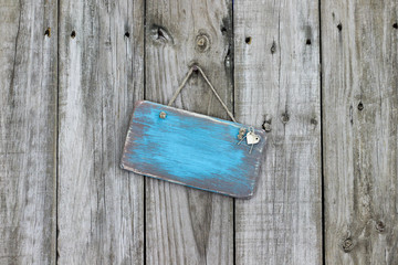 Blank teal blue sign hanging on rustic wood fence