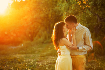 A young couple kiss in park at sunrise