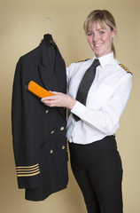 Obraz na płótnie Canvas Female airline captain brushing her uniform jacket