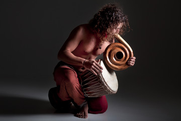 Musiker oberkörper nackt mit Spiral Didgeridoo und Conga Trommel Porträt