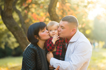 beautiful young european family outdoors kissing little boy